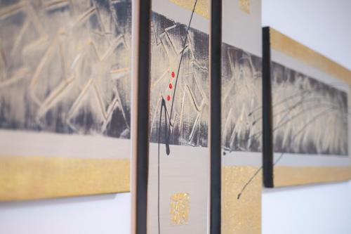 a group of framed paintings on a wall at 旭神ゲストハウス in Asahikawa
