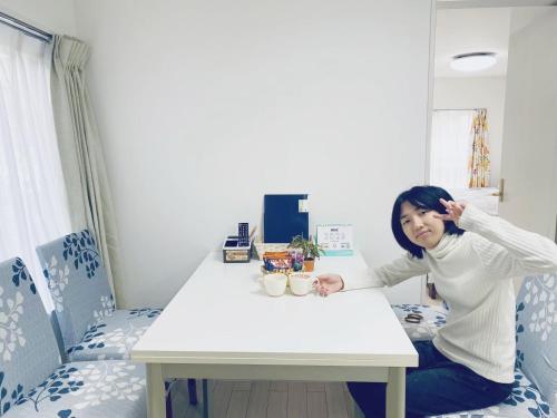 a woman sitting at a table in a room at 結奈希 Yunakis House in Tokyo