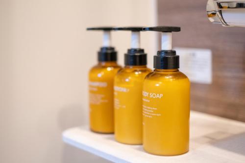 a couple of yellow bottles sitting on a shelf at 旭神ゲストハウス in Asahikawa