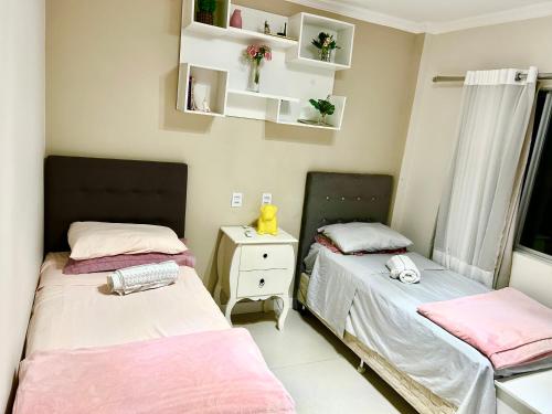 two beds in a small room with pink sheets at Beira da praia, Quarto para até 2 pessoas, econômico, básico e confortável in Balneário Camboriú