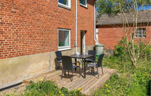 a table and chairs on a wooden deck next to a brick building at Beautiful Apartment In Hurup Thy in Heltborg