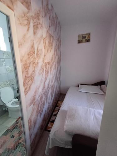 a small room with a bed and a toilet at Cazare Schitul Sf Gherasim in Cobadin