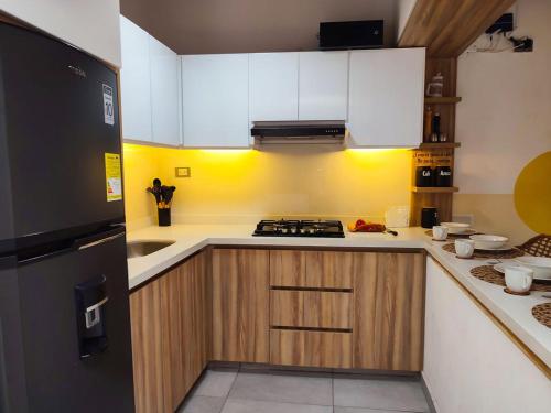 a kitchen with white cabinets and a black refrigerator at Hospédate en Oiba con estilo WIFI TERRAZA in Oiba