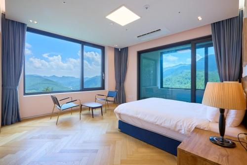 a bedroom with a bed and large windows at Romyzian Garden Mountain House in Handae-dong