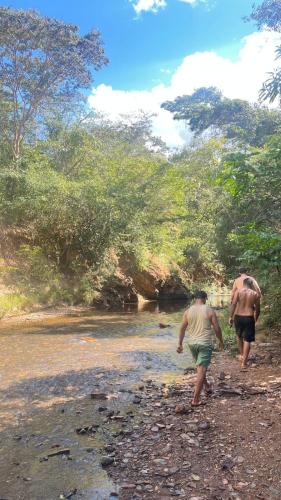 two men walking along a river with trees at Recanto Do Piu in Padre Bernardo