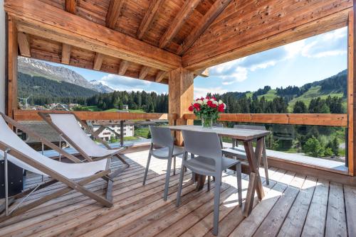 a patio with a table and chairs on a wooden deck at Turrabuel in Parpan