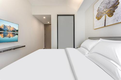 a bedroom with a white bed and a painting on the wall at 漫点 Moodlink Hotel at Taikoo Hui, Sports Center in Guangzhou