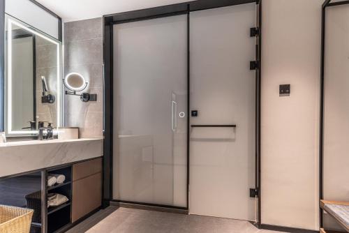 a glass shower door in a bathroom with a sink at Atour Hotel Hangzhou Xiaoshan Airport Airport Town in Hangzhou