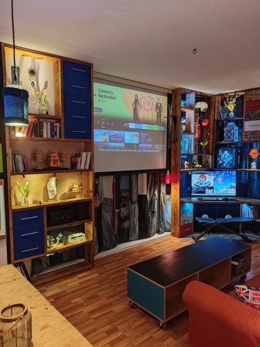 a living room with a large screen in the corner at Unique Penthouse with Home Cinema, Panoramic Views & Eco-Chic Design in London