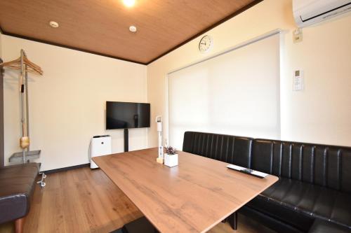 a room with a table and a couch and a television at Long-term stays welcome! Entirely private rental townhouse for up to 4 people, 17 minutes walk from station, 45 minutes direct to Tokyo in Ageo