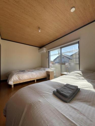 a bedroom with two beds and a large window at Long-term stays welcome! Entirely private rental townhouse for up to 4 people, 17 minutes walk from station, 45 minutes direct to Tokyo in Ageo
