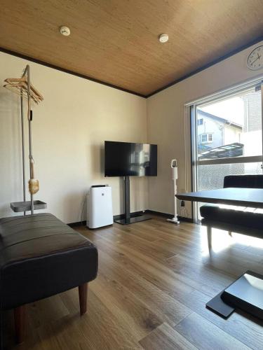 a living room with a tv and a couch and a table at Long-term stays welcome! Entirely private rental townhouse for up to 4 people, 17 minutes walk from station, 45 minutes direct to Tokyo in Ageo