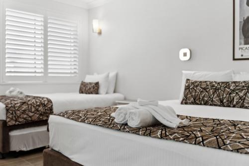 a hotel room with two beds with towels on the bed at Smugglers On The Beach in Coffs Harbour
