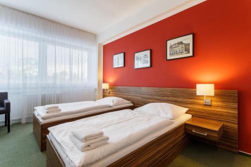 two beds in a room with a red wall at Hotel Veronika in Ostrava