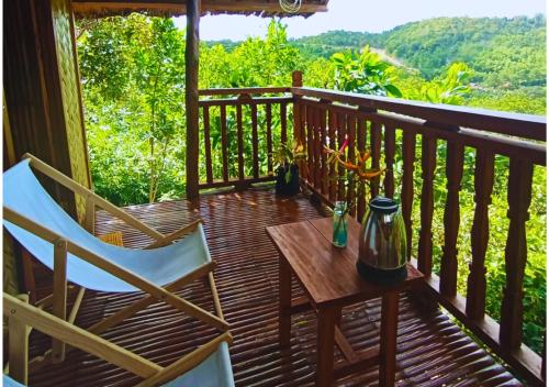 a wooden deck with two chairs and a table on it at Busuanga Nature Retreat in Busuanga