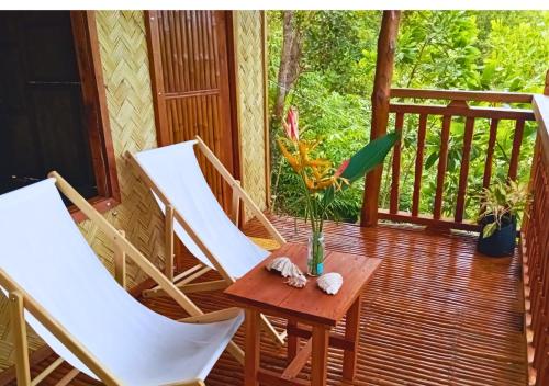 a porch with two chairs and a table with a vase on it at Busuanga Nature Retreat in Busuanga