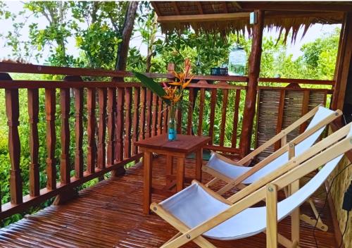 a couple of chairs and a table on a deck at Busuanga Nature Retreat in Busuanga