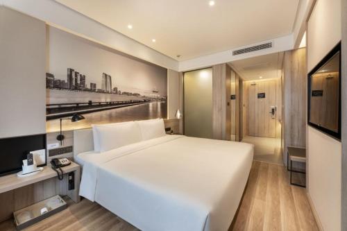 a bedroom with a large white bed and a television at Atour Hotel Suzhou Shi Road Shantang Street in Suzhou