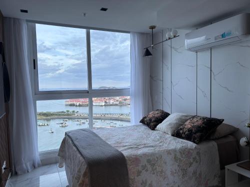 a bedroom with a large window with a view of a harbor at the sands vista al mar amplio in El Quije
