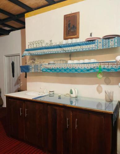 a kitchen with a sink and shelves with dishes at SHADOW MASK BUNGALOW in Pattipola