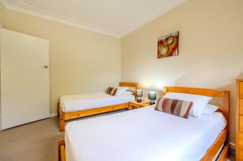 two beds in a room with white walls at Acacia Grove by the BnB Collection in Emu Point