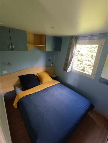 un lit dans une petite pièce avec une fenêtre dans l'établissement Mobil home tout confort, à La Celle-sous-Gouzon