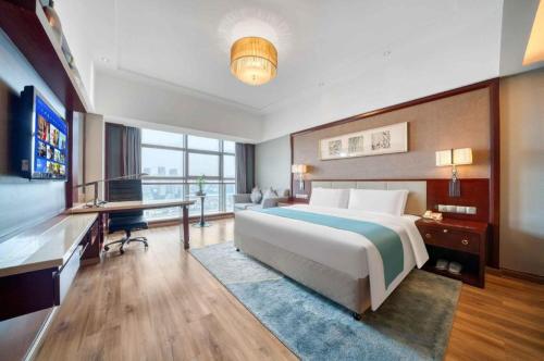 a bedroom with a bed and a desk and a television at Xiangsheng Century Hotel Zhuji in Shaoxing