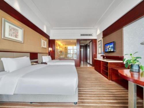 a hotel room with a large bed and a television at Xiangsheng Century Hotel Zhuji in Shaoxing