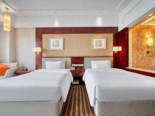 a hotel room with two beds and a desk at Xiangsheng Century Hotel Zhuji in Shaoxing