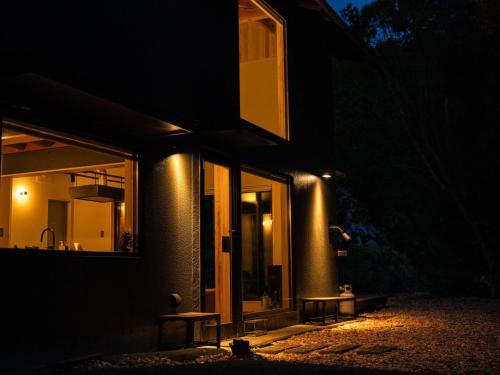 a building with two benches outside of it at night at HARUKA KANATA 森のヴィラ in Minamiboso