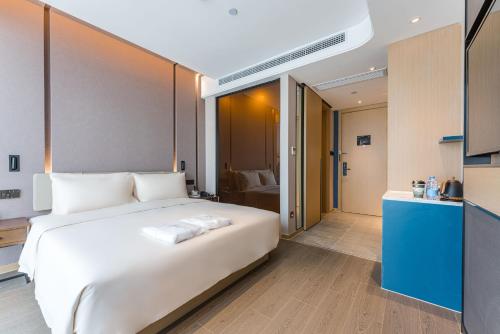 a bedroom with a large white bed and a bathroom at Atour Hotel Suzhou Wangting in Suzhou