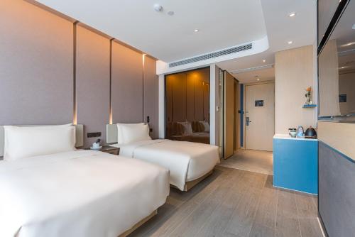 a hotel room with two beds and a kitchen at Atour Hotel Suzhou Wangting in Suzhou
