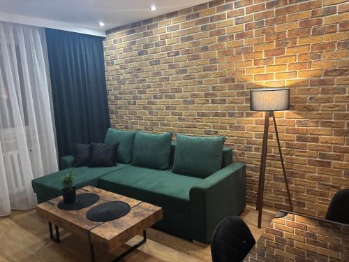 a living room with a green couch and a brick wall at Biała Centrum 2 in Biała Podlaska