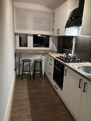 a kitchen with white cabinets and a sink and a stove at Biała Centrum 2 in Biała Podlaska