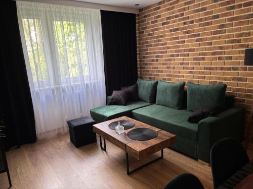 a living room with a green couch and a brick wall at Biała Centrum 2 in Biała Podlaska