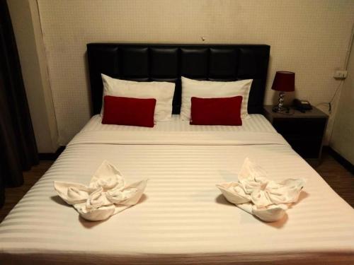 a bed with two white flowers on it at V51 Hotel in Nakhon Ratchasima