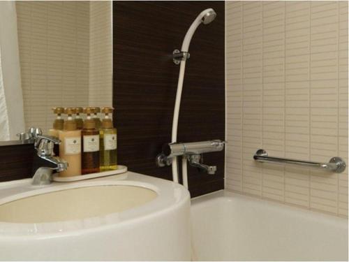 a bathroom with a sink and a bath tub with bottles at Welcome Hotel Kochi in Kochi