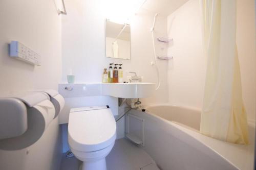 a white bathroom with a toilet and a sink and a tub at Personal Hotel You in Takeo