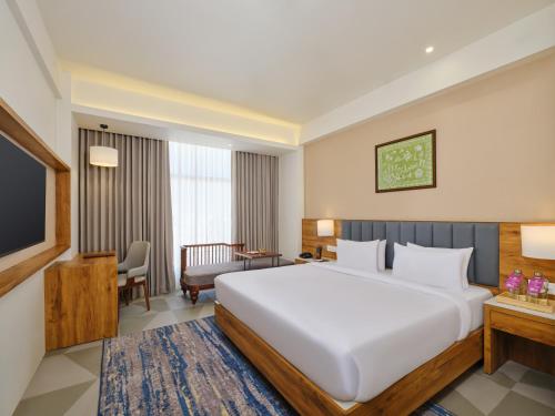 a hotel room with a large bed and a television at Regenta Dwarka in Dwarka