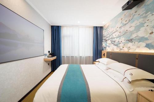 a bedroom with a large bed with a painting on the wall at JIAN AI XI YUE HOTEL in Yiwu
