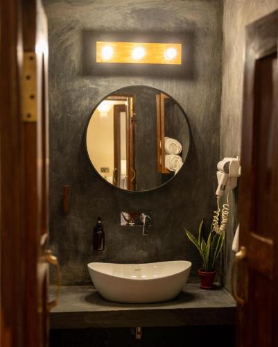 a bathroom with a white sink and a mirror at Riverside Springs Resort in Chitwan