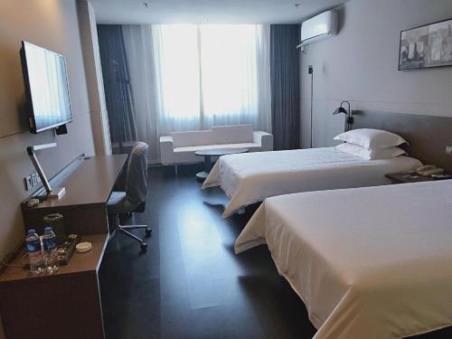 a hotel room with two beds and a desk at Jinjiang Inn Select Xuzhou High-speed Railway Station Kunpeng Road in Xuzhou