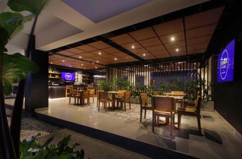 a restaurant with wooden tables and chairs and purple lights at Nadi Hotel Legian in Legian