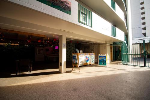 a front entrance to a building with a sign on the sidewalk at Waikiki Beachside Hostel in Honolulu