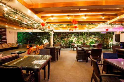 a restaurant with tables and chairs and plants at Waikiki Beachside Hostel in Honolulu