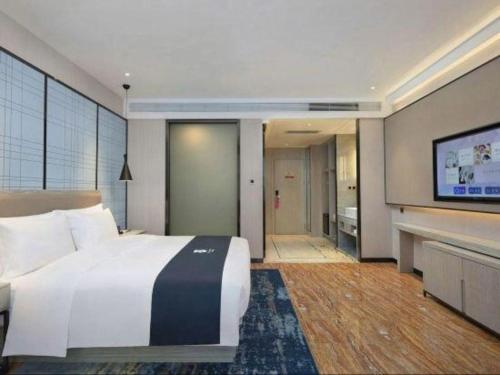 a bedroom with a large bed and a flat screen tv at Echarm Hotel Changsha High-speed Railway Station in Changsha