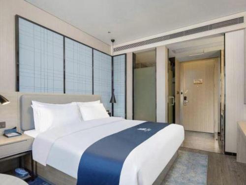 a bedroom with a large white bed and a desk at Echarm Hotel Changsha High-speed Railway Station in Changsha