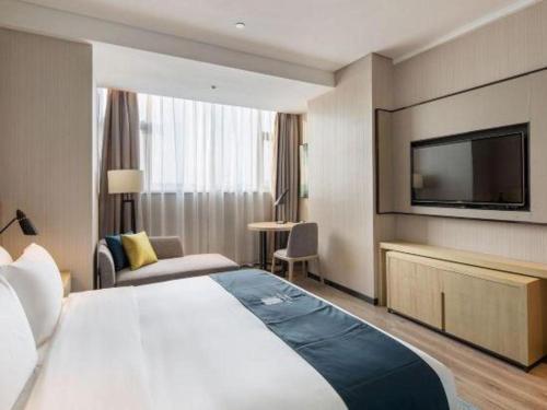 a hotel room with a large bed and a flat screen tv at Echarm Hotel Changsha High-speed Railway Station in Changsha