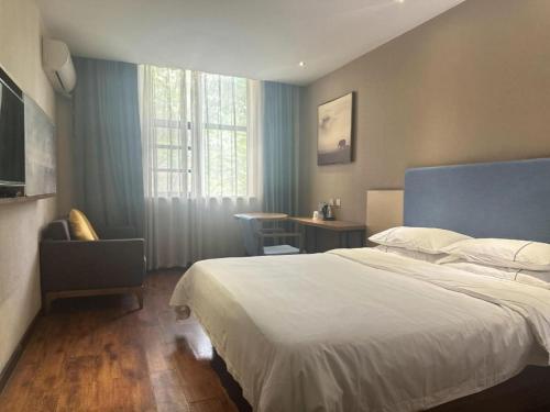 a bedroom with a bed and a chair and a window at JTOUR Inn Wuhan Changfeng Avenue Garden Expo in Wuhan