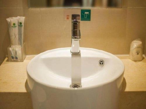 a white sink with a faucet in a bathroom at City Comfort Inn Yichang Dongshan Three Gorges University Shuiyuecheng in Yichang